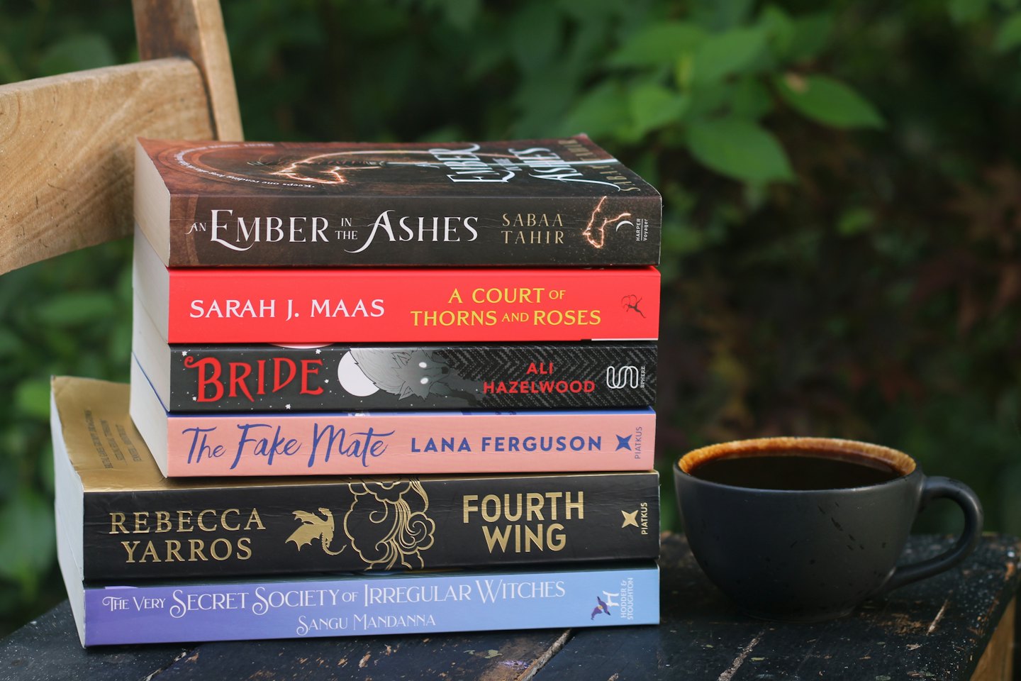 A stack of romance novels sits beside a coffee mug.